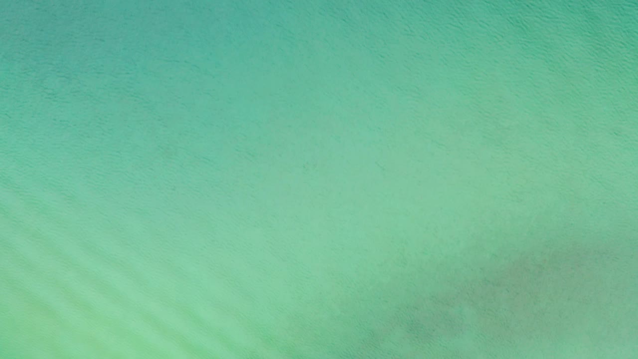 Top-down view of turquoise ocean water in La Ribera, Baja California Sur, Mexico, with faint diagonal ripples and no visible people.