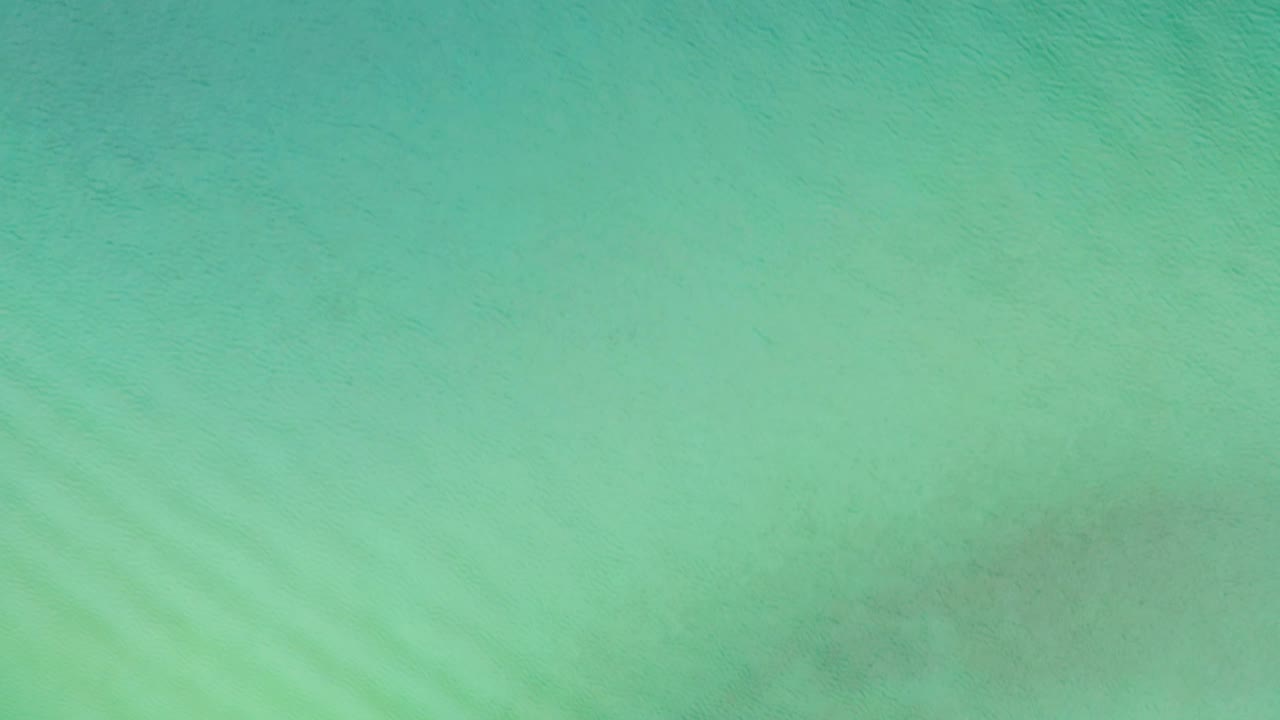 Aqua ocean surface seen from above in La Ribera, Baja California Sur, Mexico, with soft ripple bands and no visible people.