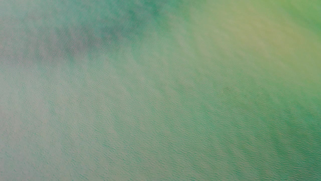 Aerial water surface in La Ribera, Baja California Sur, with green tones, pale yellow highlights, and no visible people.