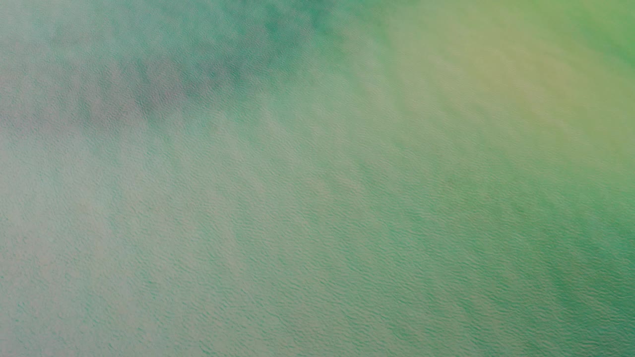Downward-looking view of teal and green ocean water in La Ribera, Baja California Sur, with a darker band near the top and no visible people.