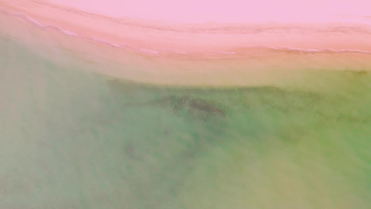 Pink shoreline and green water viewed from above