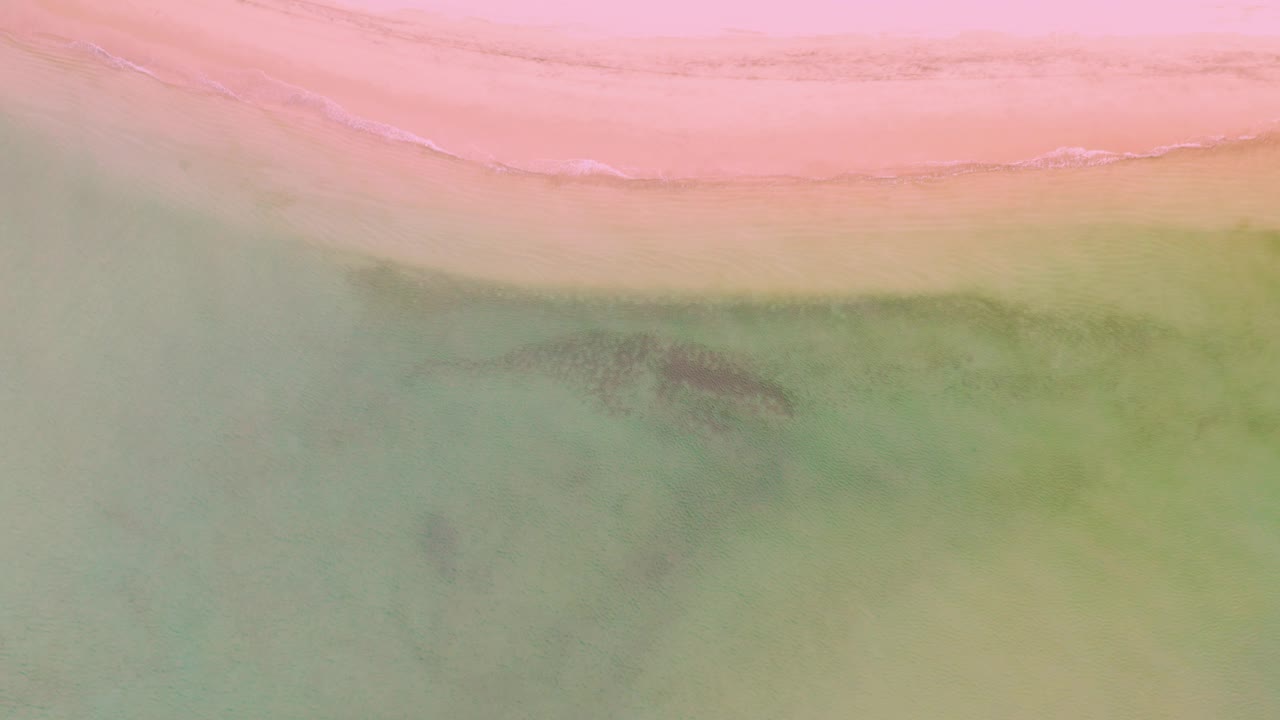 Pink beach edge with green water and darker patches