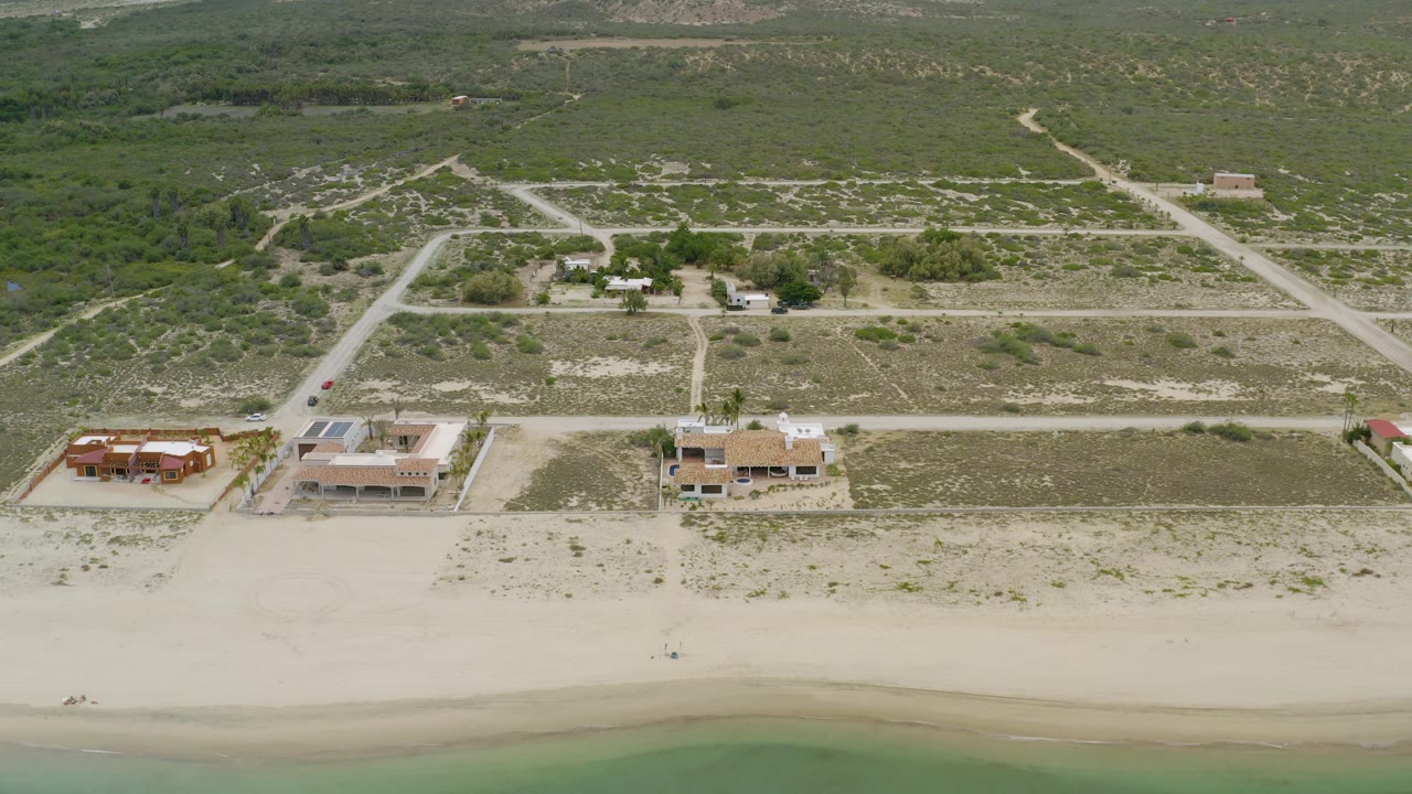 Drone view of beach houses, shoreline, and inland scrub road pattern