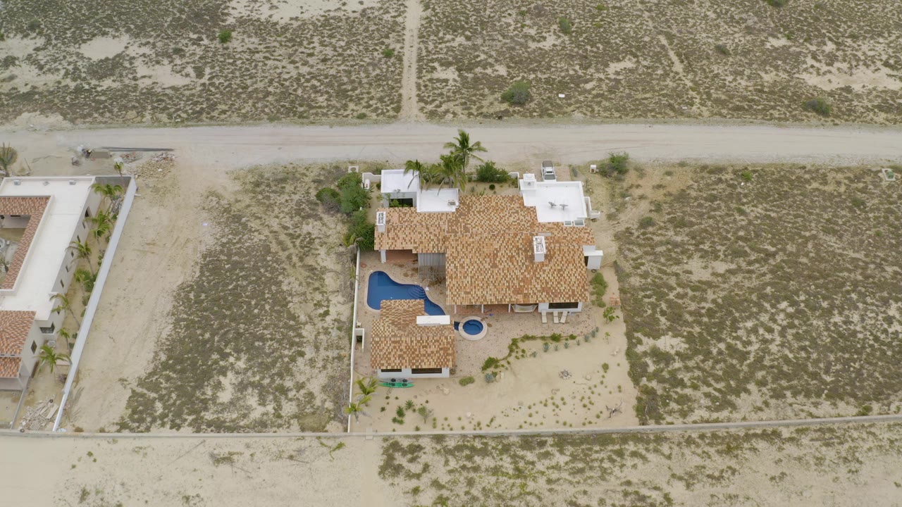 Top-down residential aerial with a house, pool, road, and desert scrub parcels.