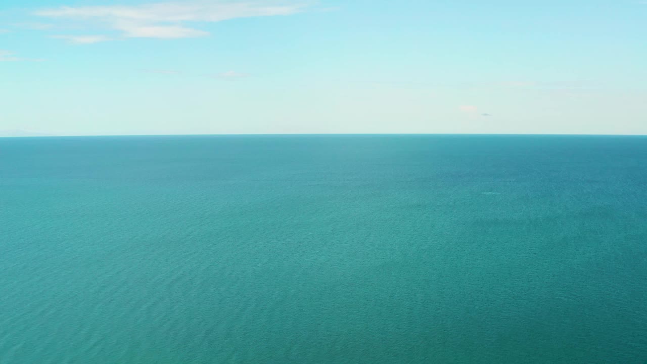 Turquoise ocean extends to a straight horizon line in La Ribera, Baja California Sur, with pale sky overhead and no visible people.
