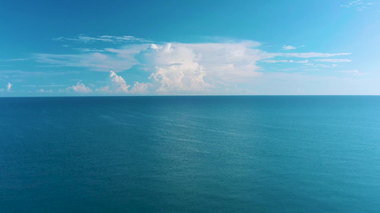 Aerial ocean view in La Ribera, Baja California Sur, showing textured blue water, a broad cloud mass near the horizon, and no visible people.