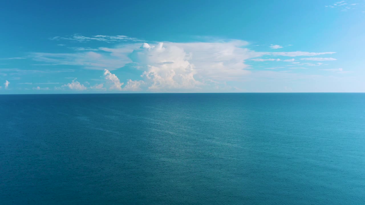 Open turquoise-blue water fills the lower frame in La Ribera, Baja California Sur, with white clouds along the horizon line and no visible people.