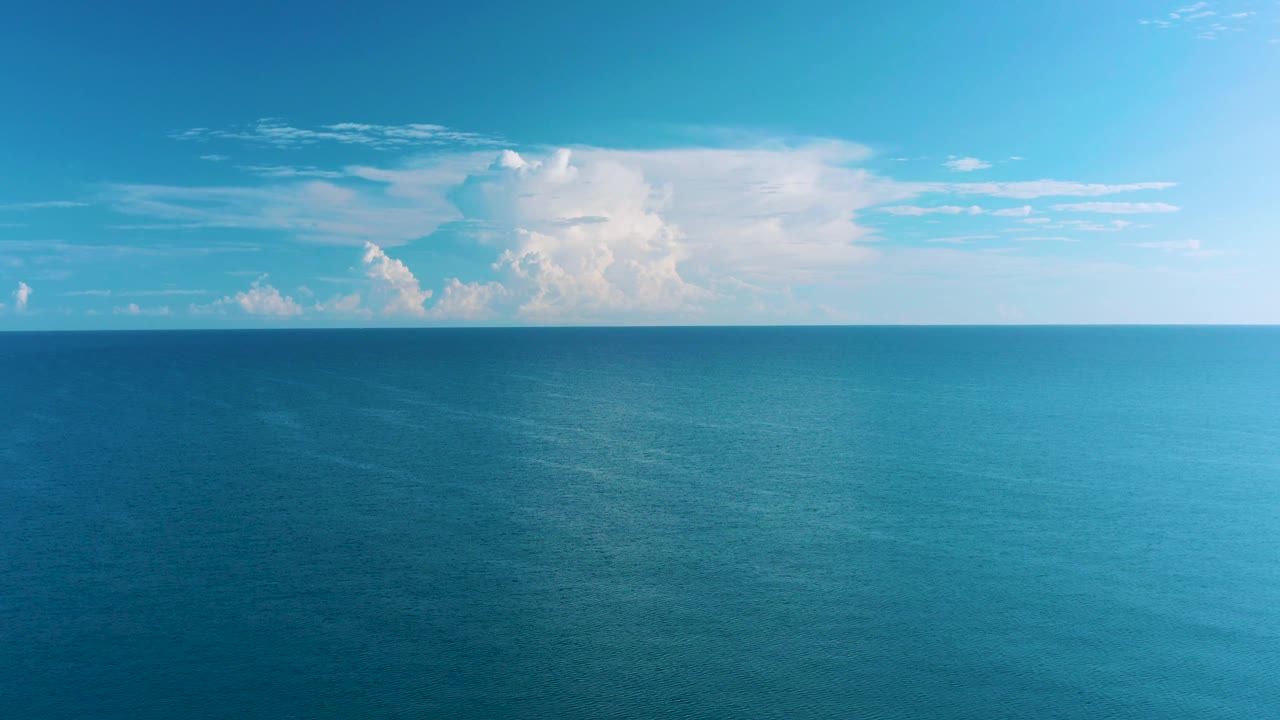 A wide ocean surface in La Ribera, Baja California Sur, sits beneath a central white cloud formation, with brighter light on the right and no visible people.