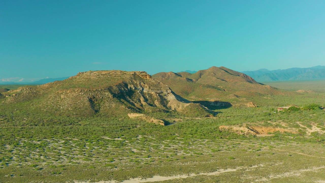 Wide view of rocky hills and scrub-covered open ground in La Ribera, Baja California Sur, Mexico, with distant ridges and no visible people.