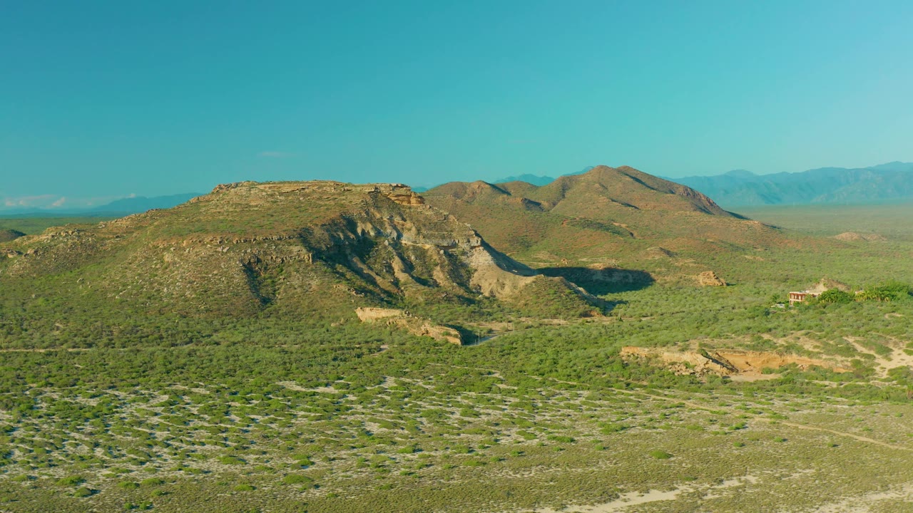 Rocky hillside with brushy terrain and distant mountains.