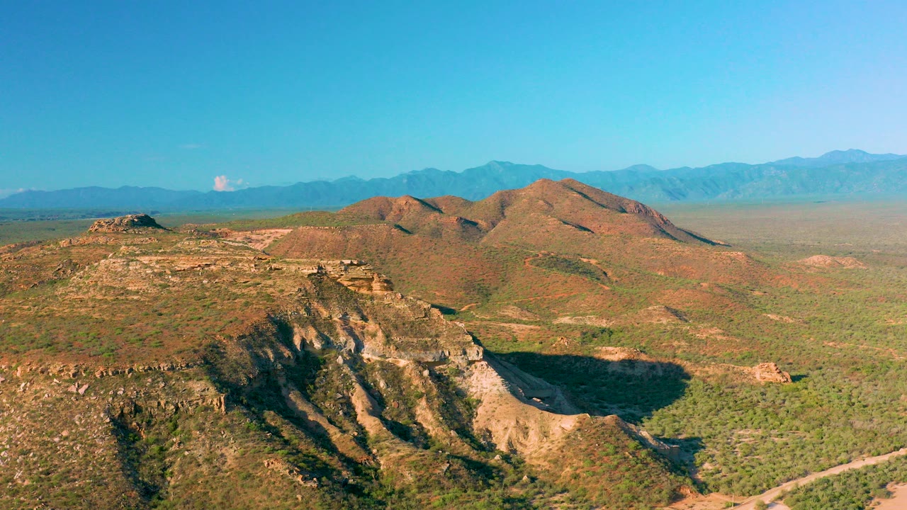 Aerial view of scrub-covered hills, plateau, and distant mountains