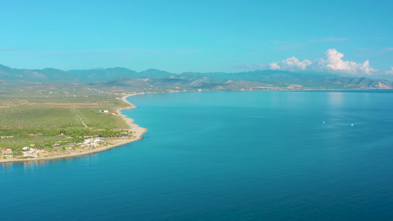 Aerial view of shoreline, green land, and blue water