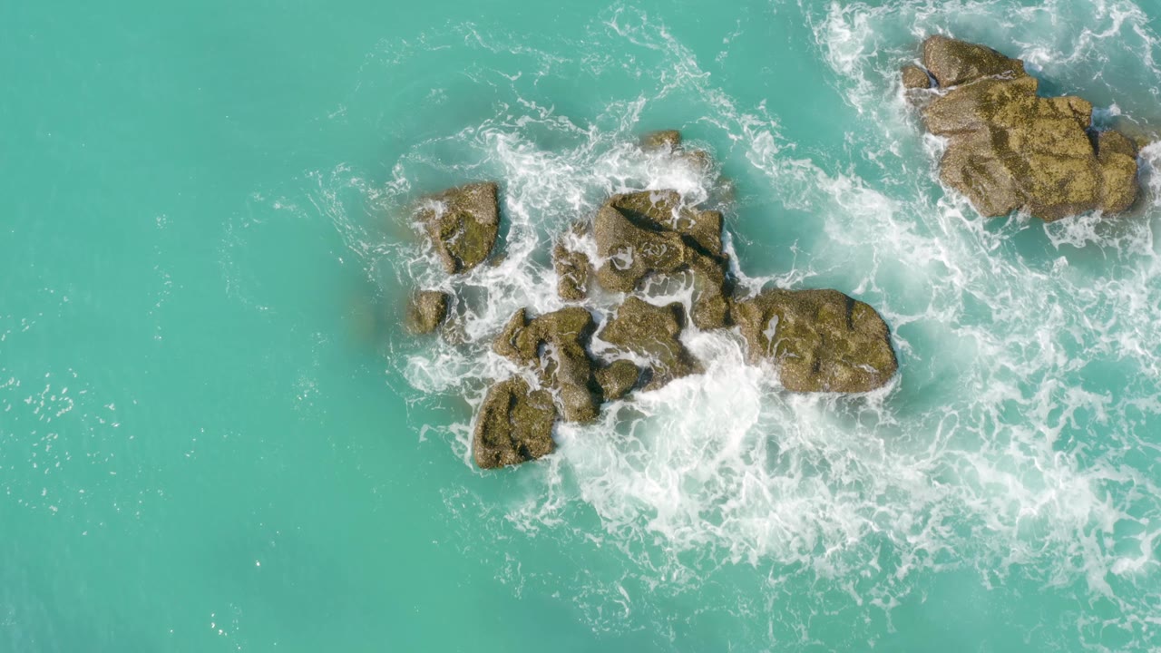 Aerial view of waves washing over jagged rocks.