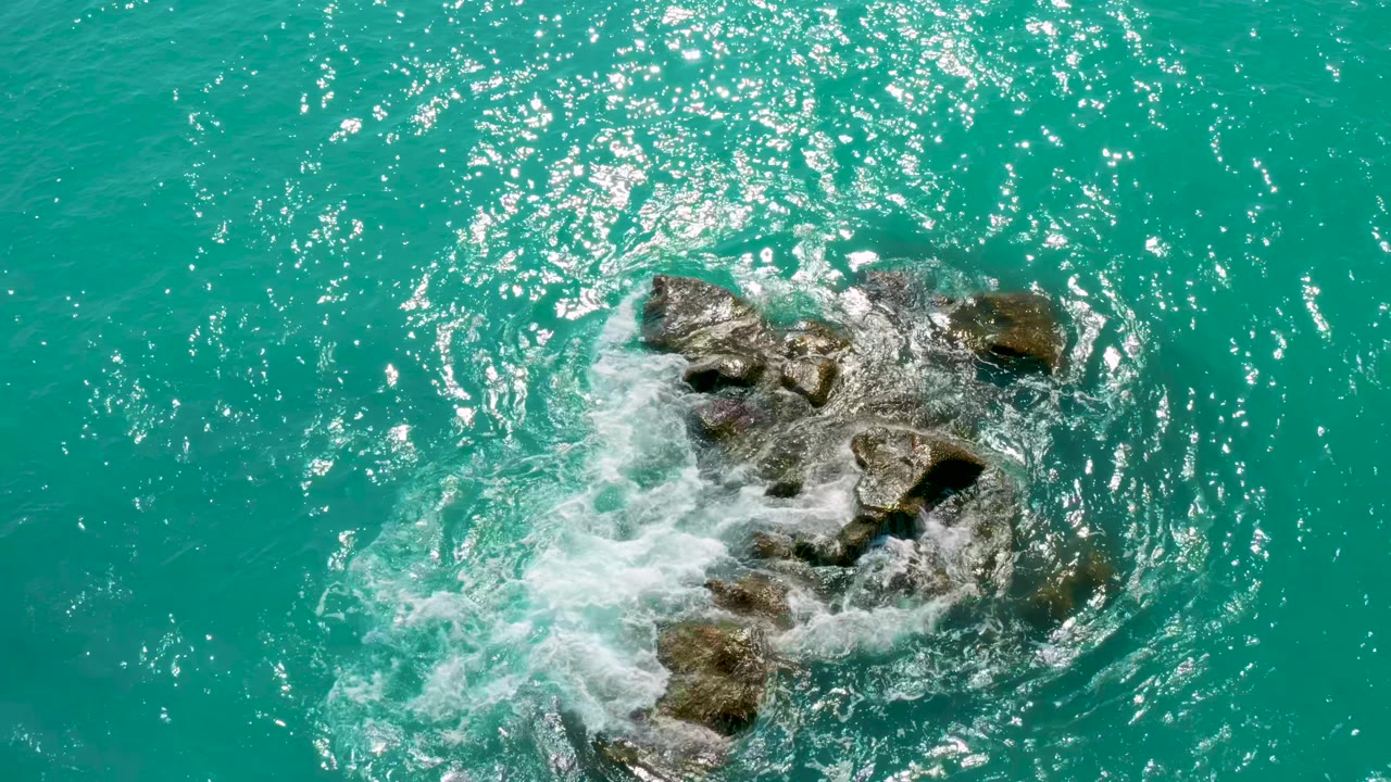 Foam spreading over central rocks in bright green water