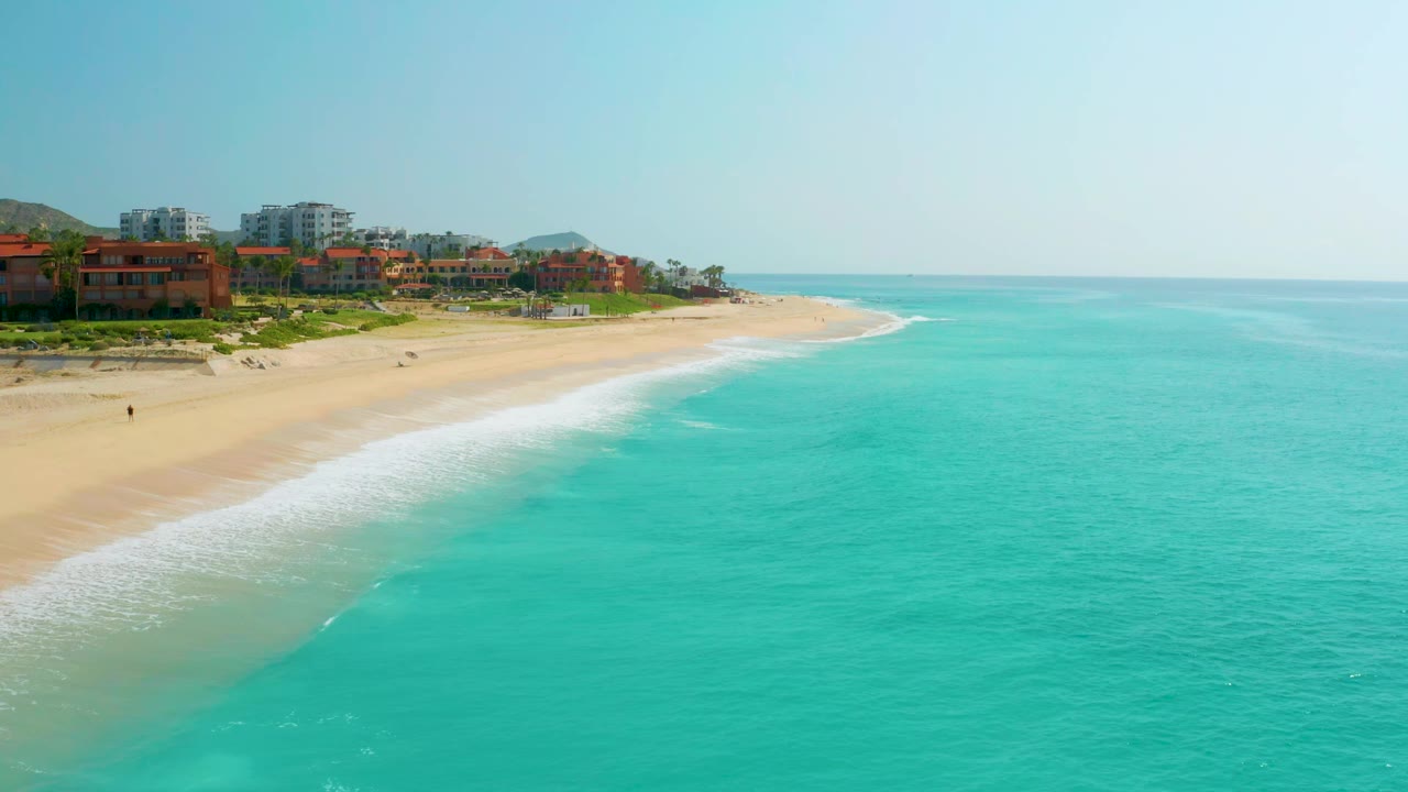 Wide aerial coastline with surf line curving along an empty sandy beach