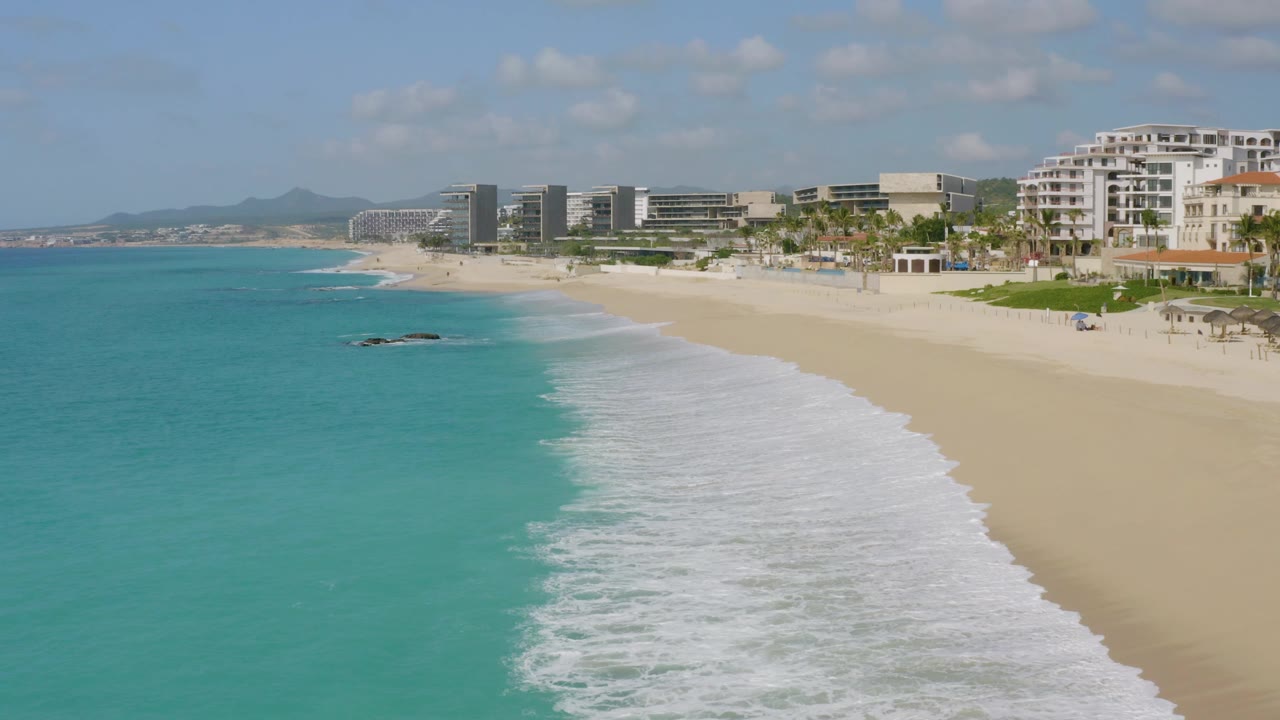 The third frame holds a wide aerial angle over Dreams Beach, with white surf bands spreading across the sand, turquoise sea to the left, and resort buildings beyond the beach, with no visible people.