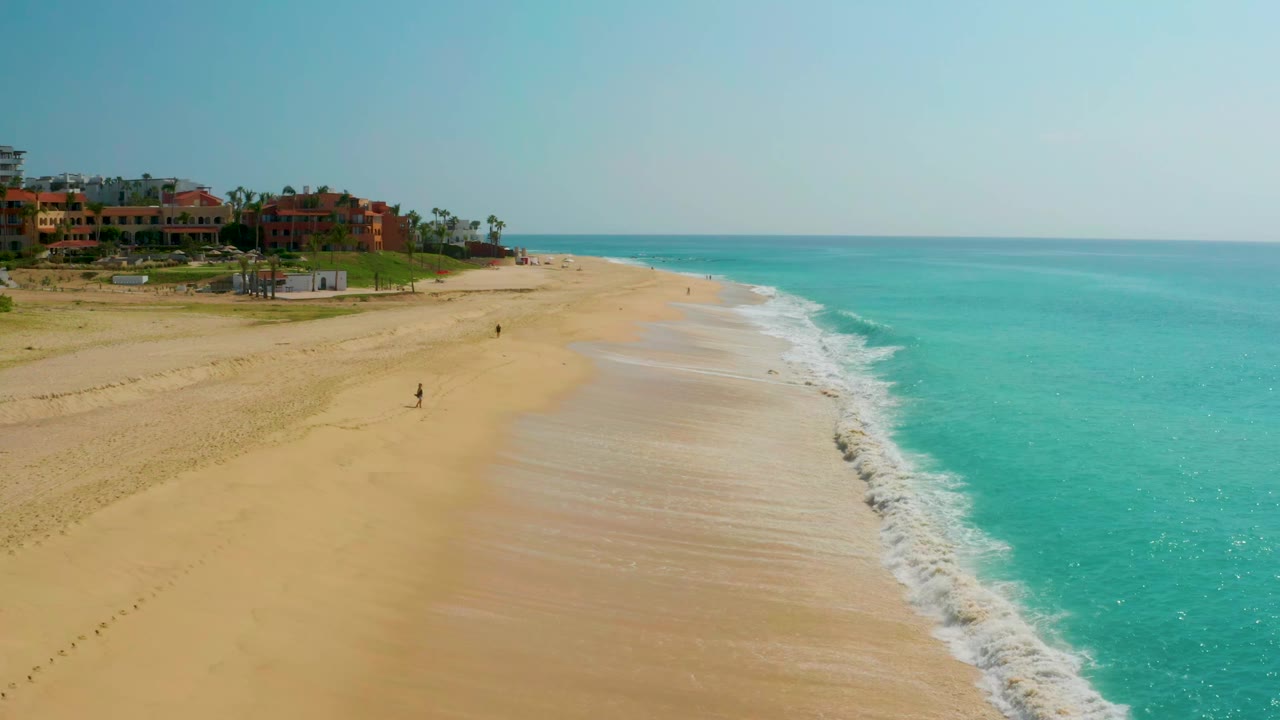 Wide beach and ocean view with white waves along the shoreline.
