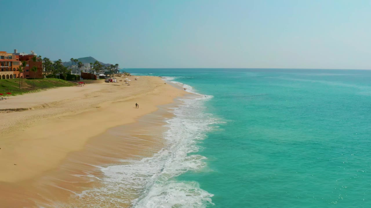 Blue waves form a white edge along the sandy shoreline.