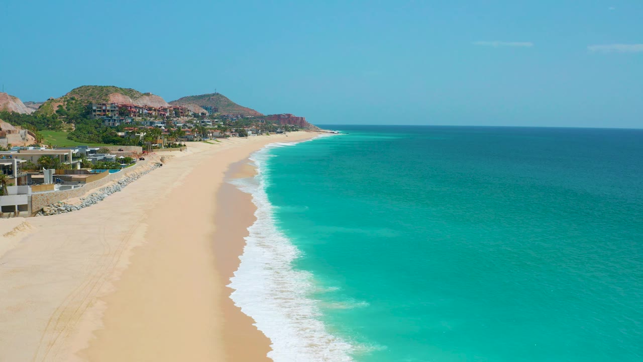 Long empty beach with turquoise water and coastal homes