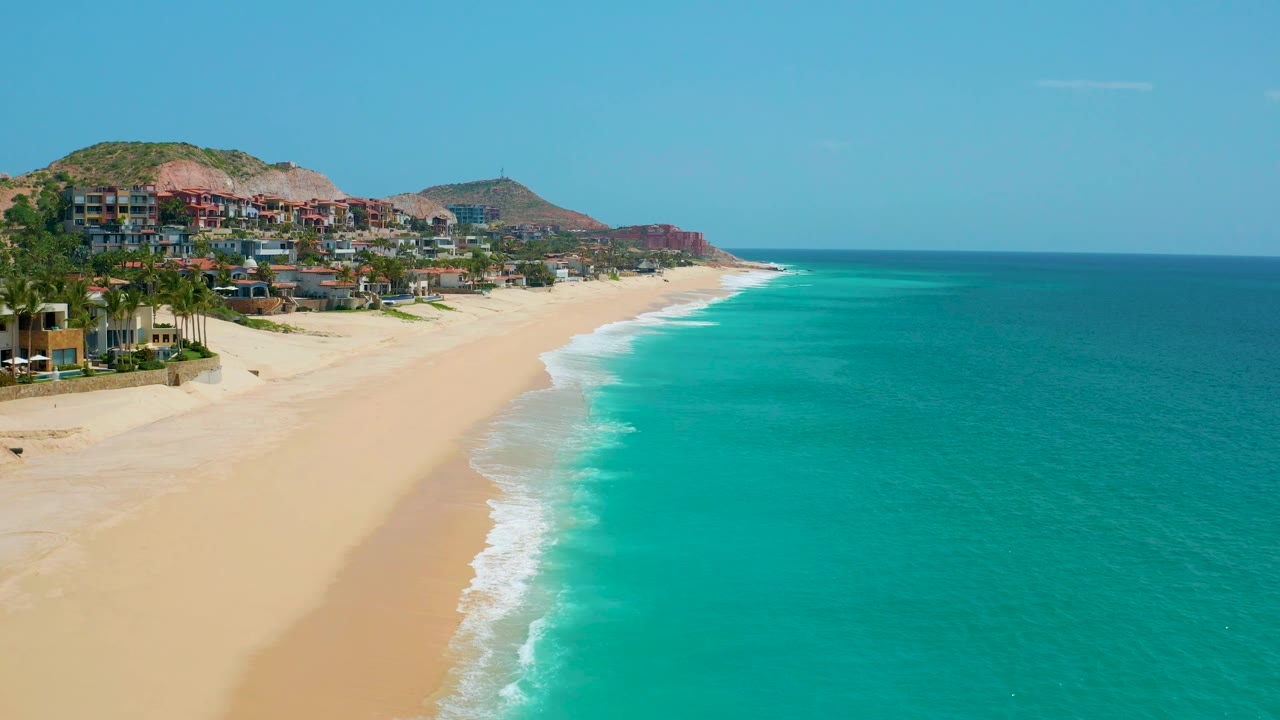 Aerial coastline with beach villas and rolling surf