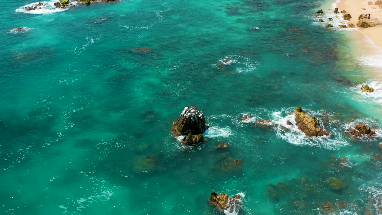 Overhead ocean view with central rock outcrop and surf.