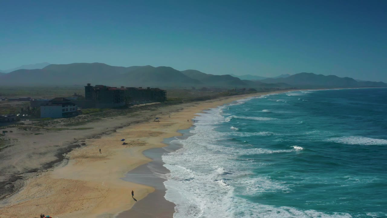 Oblique aerial coastline with waves breaking along a broad beach