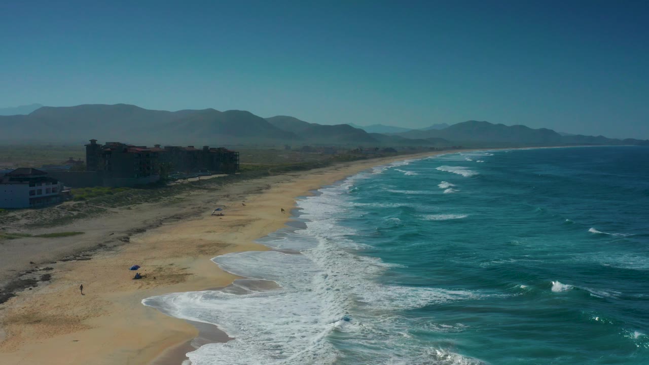Aerial shoreline view with waves reaching a broad sandy beach