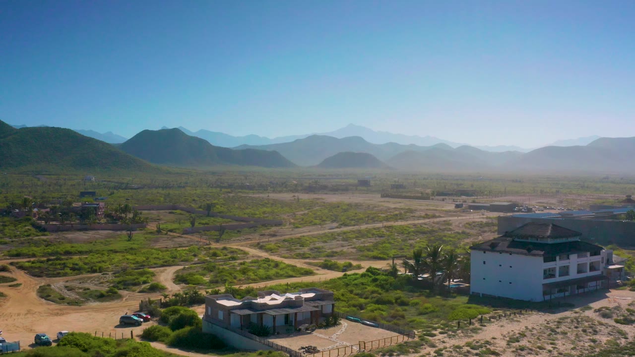 Aerial view of dry roads, homes, palms, and distant mountains