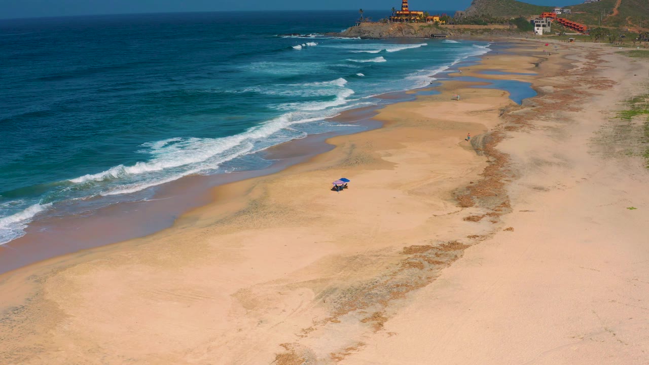 Aerial beach view with surf and a small object on sand