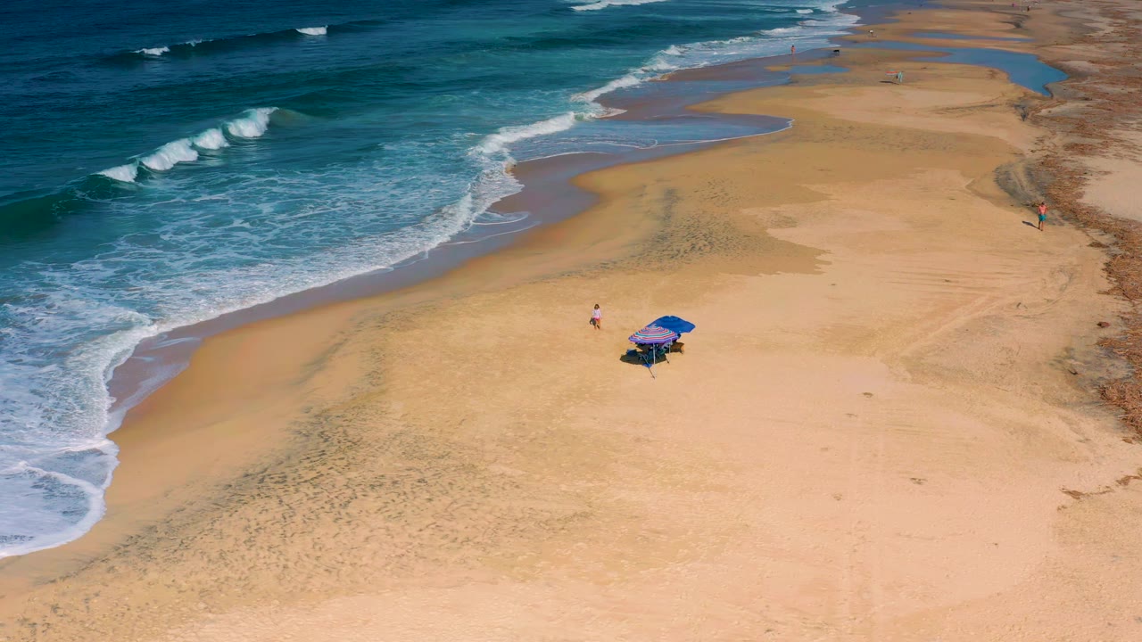 Diagonal beach shoreline with surf and umbrellas on sand