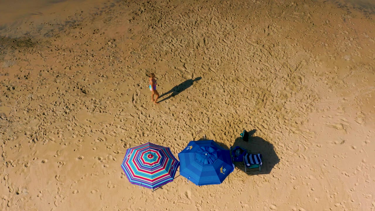 Woman walking on sand near colorful beach umbrellas