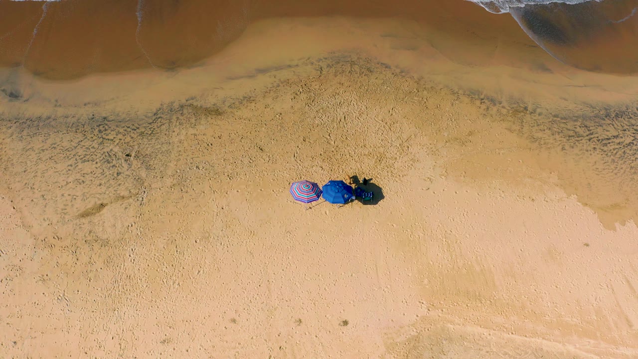 Overhead sand and shoreline with small beach gear cluster