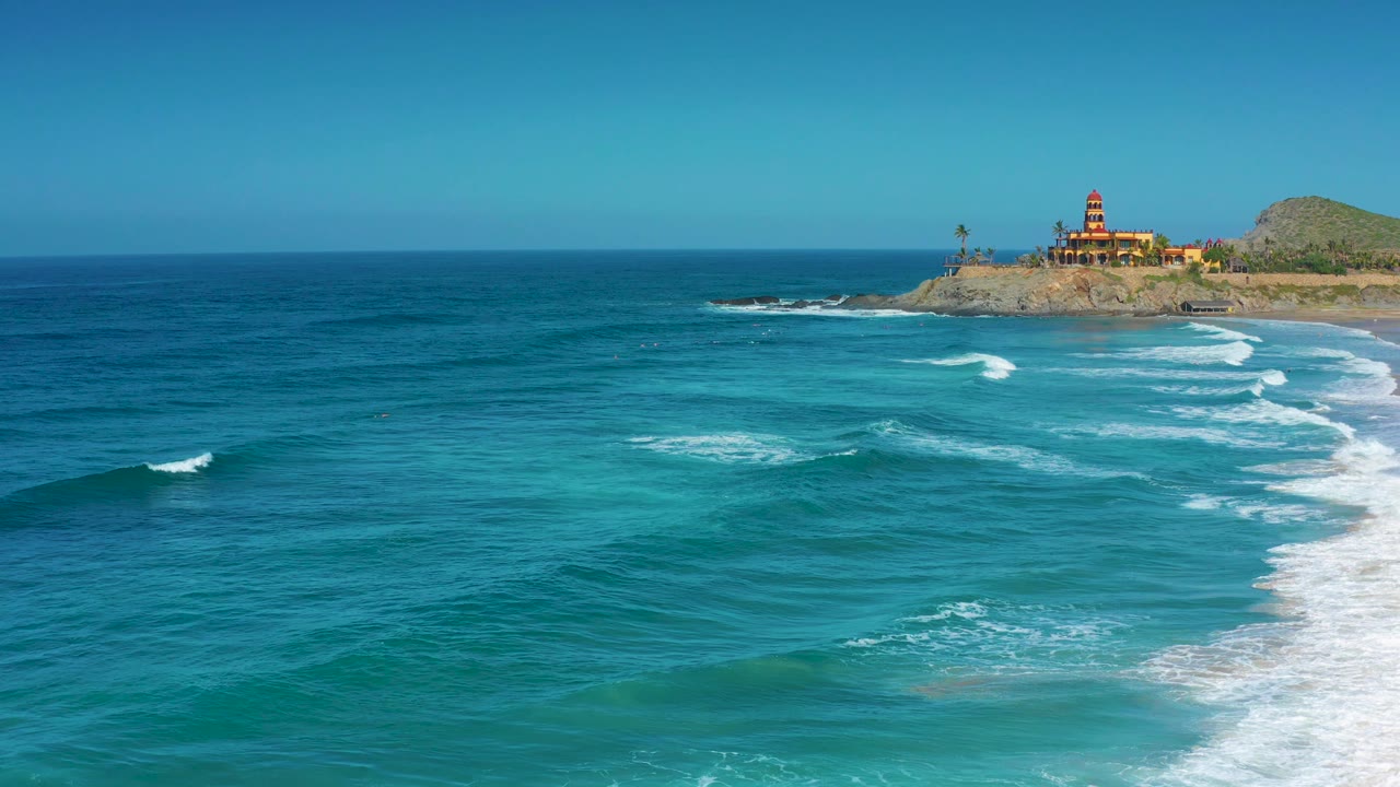 At 0:03, more open water fills the foreground while a line of small waves moves toward the right edge and the Cerritos bluff remains near the horizon, with no visible people.