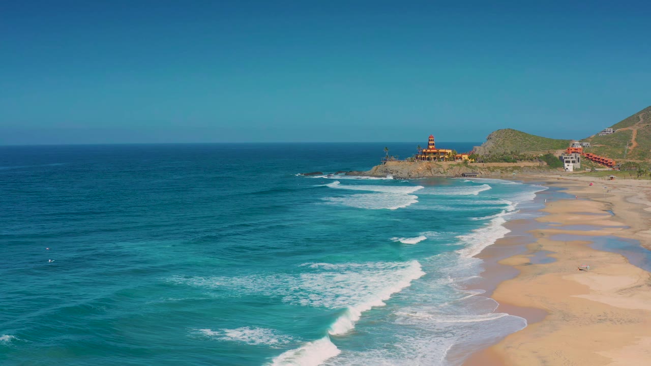 Aerial coastline view with rolling surf beside a wide sandy beach