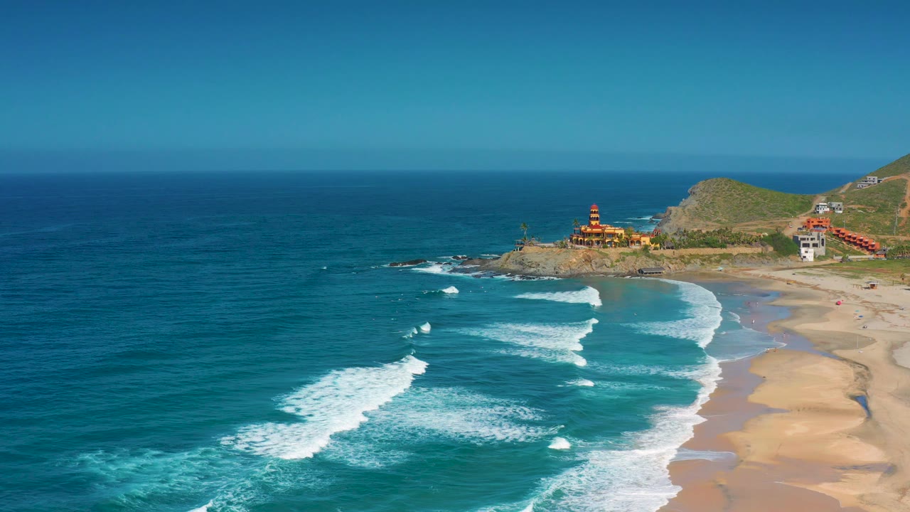 High view of ocean swells curling onto a sandy Mexico beach.