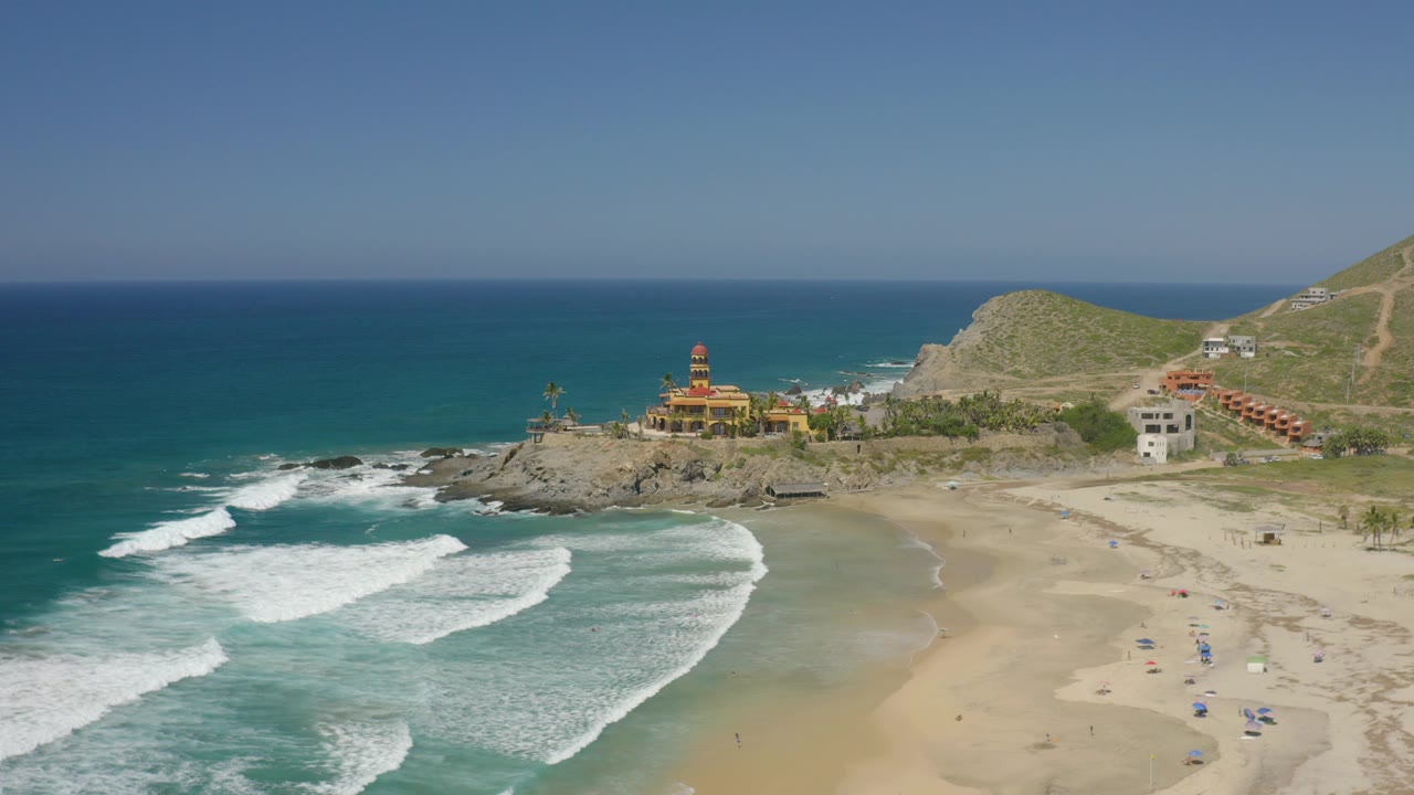 Aerial view of waves reaching a sandy beach beside rocky coast