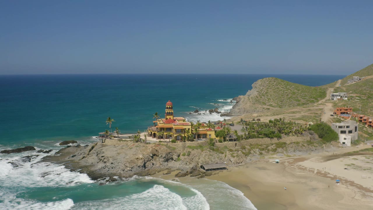 Wide aerial view of the same coastal structure with waves on rocks.