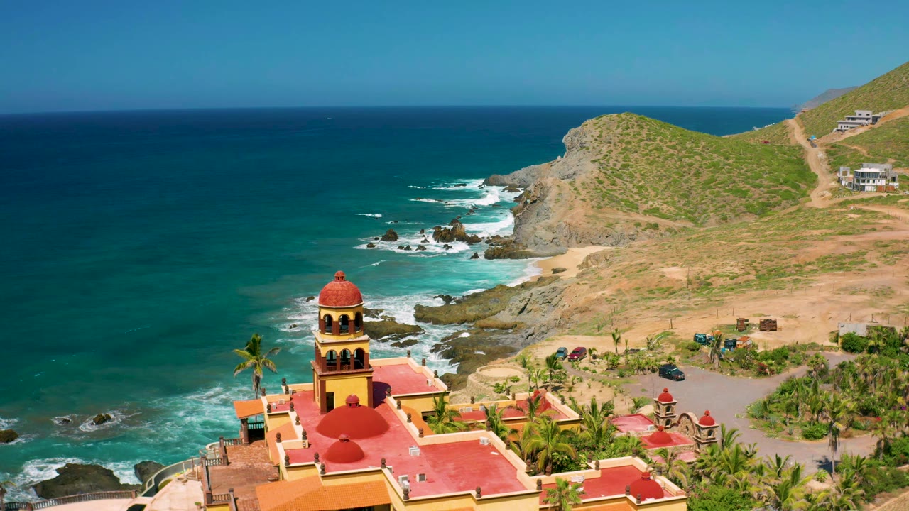 Aerial view of domed building, palms, ocean, and headland