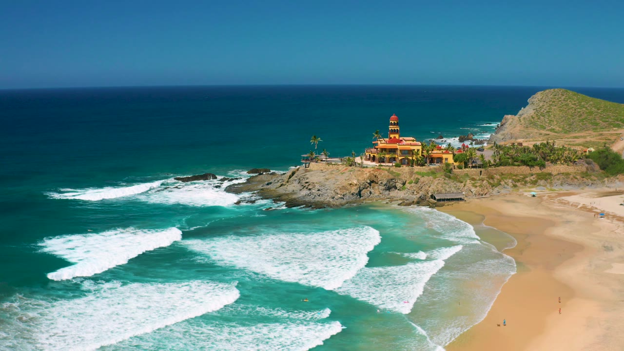 At two seconds, foamy water covers more of the lower beach edge while the towered building and hill sit along the upper-right Cerritos shoreline, with no visible people.
