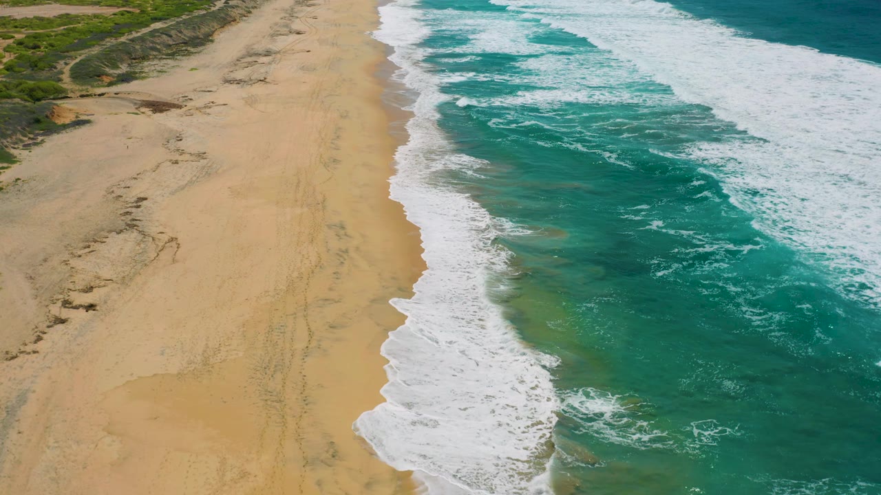Foamy surf washing along an empty sandy shoreline