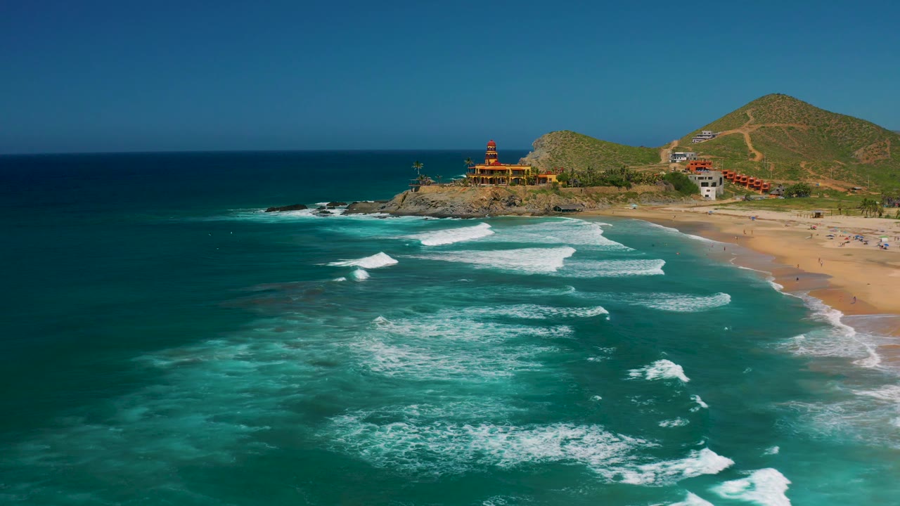 Aerial ocean foreground with white waves running toward the beach.