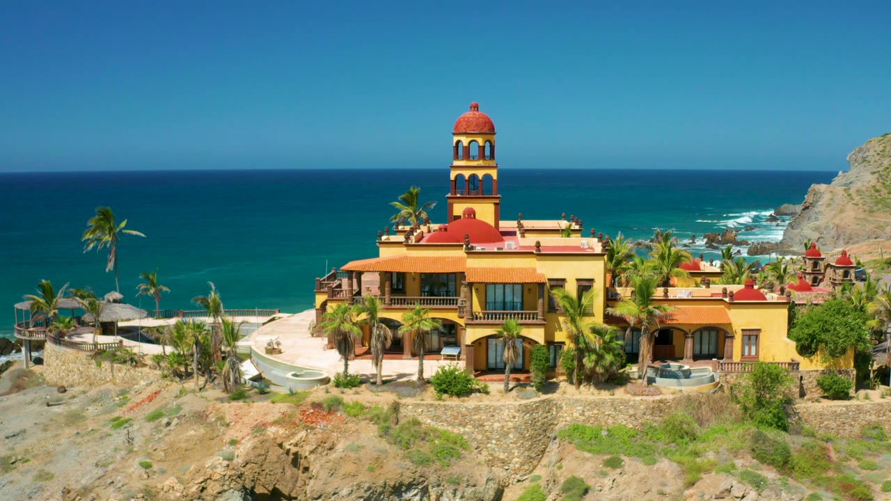 Coastal building, tower, palm trees, rocks, and ocean