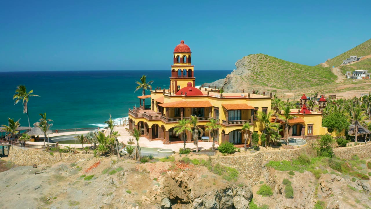 Towered beach building with palms, ocean horizon, and hillside homes