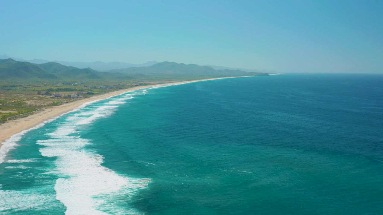 At 0:03, white surf fills more of the lower left foreground while open turquoise ocean extends across the right side of the Cerritos aerial view, with no visible people.