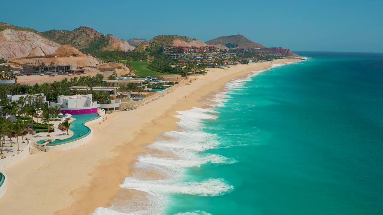 At 0:02 the composition shifts slightly along the Secrets Marquis Los Cabos shoreline, showing more open turquoise water to the right and no visible people on the sand.