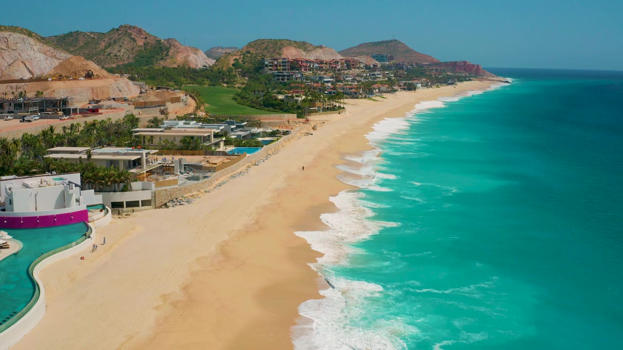 Aerial coastline view with pool foreground, beach, ocean, and hills.