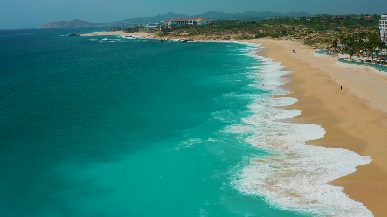 Aerial beach view with turquoise water and waves washing ashore.