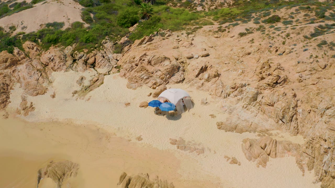 Small beach setup on sand below rocky scrubland.