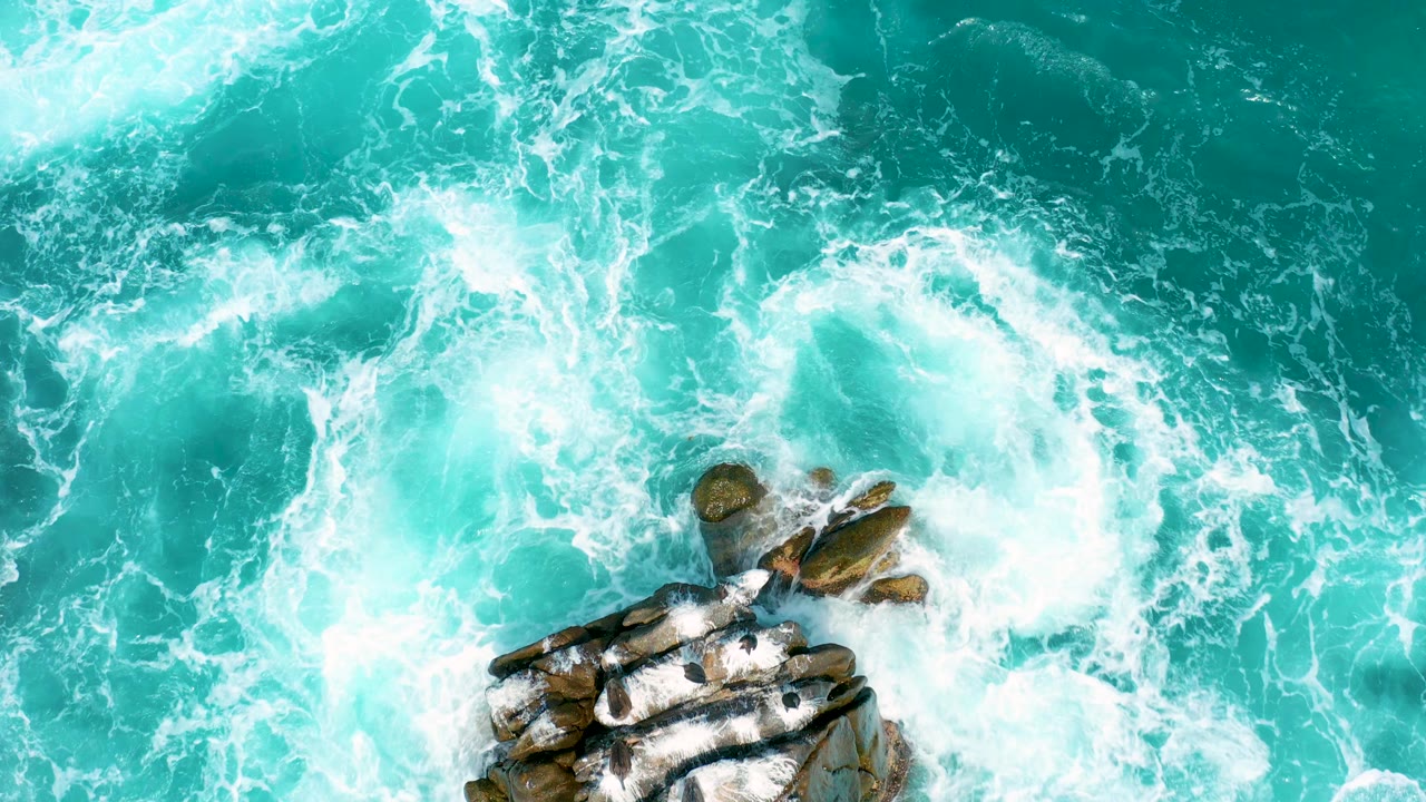 Rock edge and dense white foam in clear coastal water