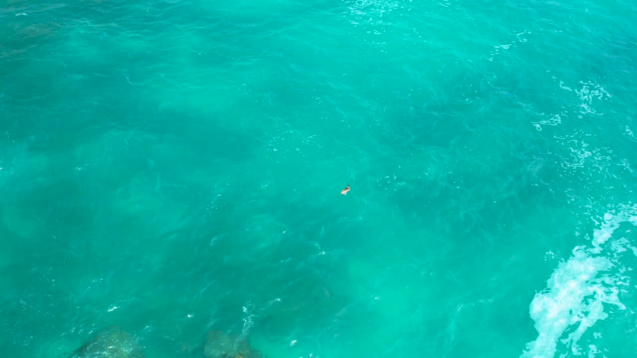 Top-down frame of green-blue ocean near Secrets Marquis Los Cabos, showing darker underwater areas, pale foam at the right edge, and no visible people.